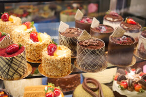 Diverse selection of pastries and cream-filled eclairs on display in a bakery shop.